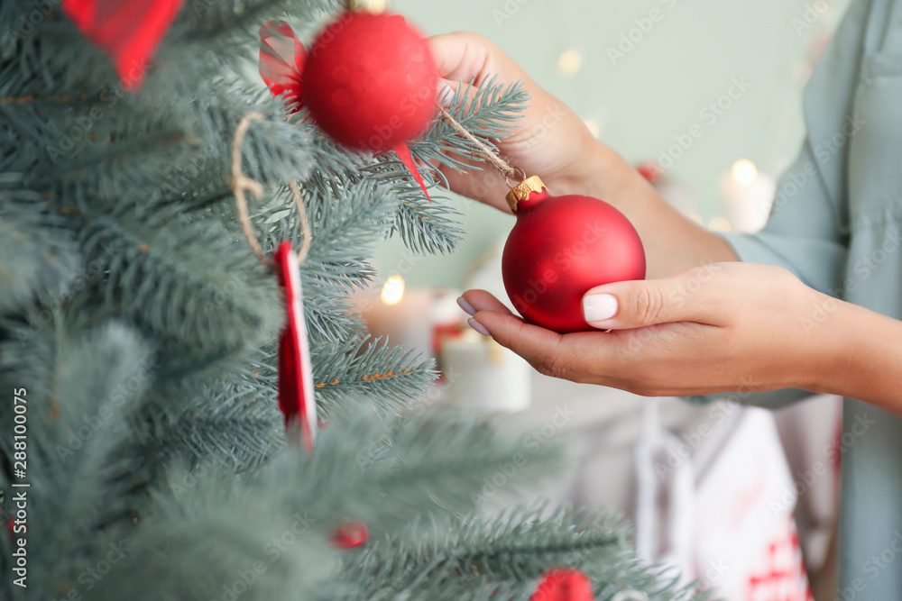 Woman decorating beautiful Christmas tree at home, closeup