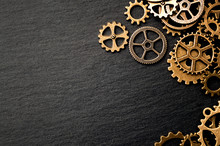 Steampunk Accessories And Old Technology Conceptual Idea With Border Made Of A Group Brass Cog Wheels On Dark Texture Background With Copy Space