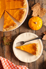 Wall Mural - traditional pumpkin pie and slices on wood background
