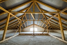 Attic Of A Building With Wooden Beams Of A Roof Structure And A Small Window.