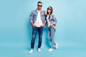 Full length photo of charming spouses looking with beaming smile wearing denim jeans eyeglasses eyewear isolated over blue background