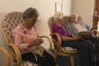 © WavebreakMediaMicro - Senior friends knitting and looking photo album at nursing home