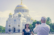 A man photographs a woman against the background of the Orthodox Church