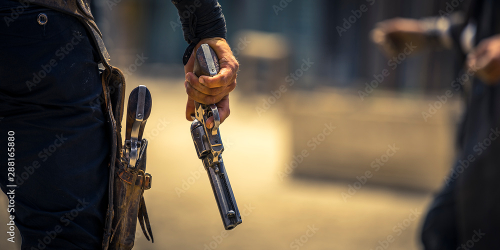 Man holding his six-shooter ready for a gunfight, Western movie set - obrazy, fototapety, plakaty 