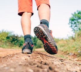 Wall Mural - trekking boot sole close up image traveler feet in trekking boots on mountain dirty path at summerti