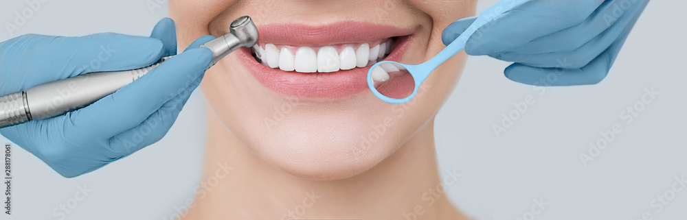 Cropped perfect smile and dentist hands holding a dental drill and an angle mirror. Dentistry and teeth treatment - obrazy, fototapety, plakaty 