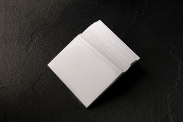 Wall Mural - A mock-up of a stack of white business cards on a black slate background, shot from the top with a place for text