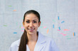 © MyMicrostock/Stocksy - Happy young nurse In white uniform over a scheme drawing on wall