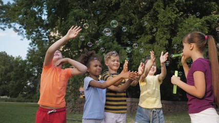 Poster - Cute little children playing with soap bubbles in park, slow motion