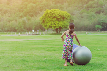 Wall Mural - Happiness girl in the floral skirt relax and play with a big ball on green field in the public garden.