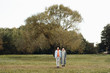 © Alina Hvostikova/Stocksy - Couple holding hands on field near tree