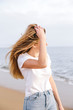 © Curtis Kim/Stocksy - Blonde girl taking a stroll on the shoreline at the beach