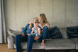© Westend61 - Happy family of three sitting on couch at home