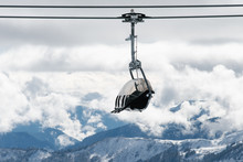 Moving Chairlift Against Mountains And Clouds