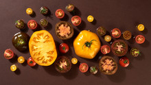 Pattern Of Slices Of Ripe Yellow And Red Tomatoes On A Dark Brown Background With Copy Space. Healthy Ingredient. Flat Lay