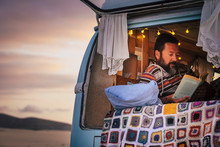 Mature Man Lying In Van And Reading A Book