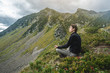 © Artem - Man hiker sitting in a yoga pose at the peak of the mountain in the summer. Meditation after a long climb on a mountain