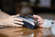 © fizkes - Close up woman paying by contactless card, terminal on bar counter