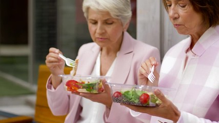 Poster - old age, leisure and food concept - senior women or friends eating takeaway salad on city street