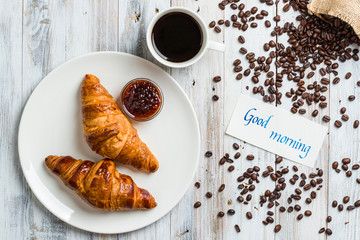 Wall Mural - Classic croissants with jam and coffee on a light wooden background with the inscription «good morning» with copy space