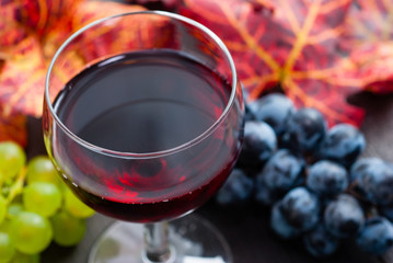 Wall Mural - glass of red wine and grapes on black wooden table background