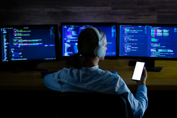 Wall Mural - software developer freelancer with white headphones and glasses working with program code: c++ java,