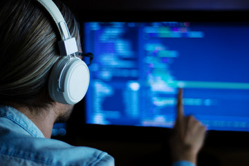 Wall Mural - software developer freelancer with white headphones and glasses working with program code: c++, java