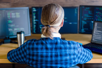 Wall Mural - back view of man freelancer in white headphones is working at home office. programmer developer is w