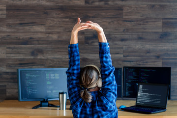 Wall Mural - back view of man freelancer in white headphones is working at home office. programmer developer is w