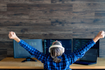Wall Mural - back view of man freelancer in white headphones is working at home office. programmer developer is w