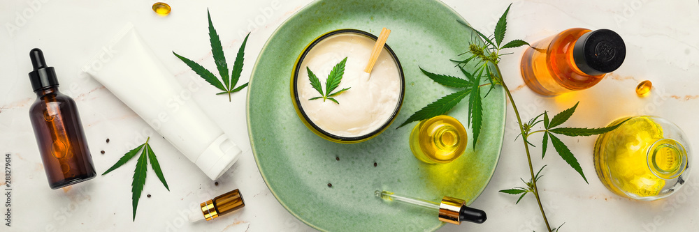 Bank of medicinal cream with CBD oil, bottle of cannabis oil, capsules, on a green plate. Flat lay, top view. Banner - obrazy, fototapety, plakaty 