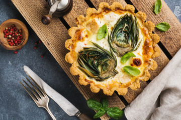 Wall Mural - Homemade quiche tart with with artichoke on light wooden background. Vintage style. Top view.