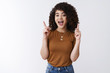 © Cookie Studio - Enthusiastic good-looking curly european young woman open mouth wow yeah excited pointing up index fingers indicating upwards enthusiastic advertising awesome product, white background