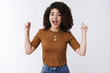 © Cookie Studio - Hooray good news. Attractive successful happy young girl dark curly hair cheering supporting friend clench index fingers raised victory gesture celebrating congratulating friend smiling joyfully