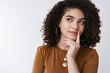 © Cookie Studio - Close-up thoughtful creative young curly-haired stylish girl pondering new ideas look upper left corner thinking touch lip index finger imaging new design project, standing white background curious