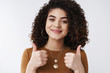 © Cookie Studio - Supportive glad stylish curly dark hairstyle girlfriend show thumbs up approval like gesture smiling agree give positive reply satisfied boyfriend booked awesome hotel summer holidays vacation