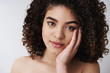 © Cookie Studio - Headshot sensual tender feminine curly-haired brunette woman touch clean pure skin cheek tilt head look cute delighted camera take care facial flaws apply makeup gazing mirror own self-acceptance