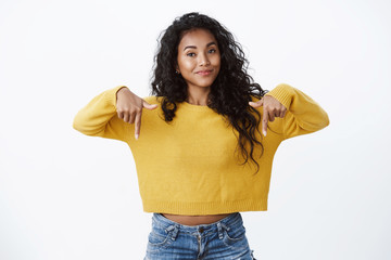 Confident cute african american female student have perfect advice, give you recommendation visit site, click page or advertisement, smiling satisfied and pleased, pointing down white background