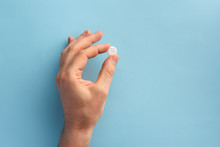 Male Hand Holding One Pill. Flat Lay.