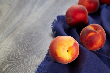 Wall Mural - Lovely ripe peaches lie on a blue linen kitchen napkin on the table. Natural fruit. Horizontal image.