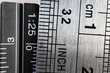 Close-up picture of two steel rulers showing the size difference between inches and centimeters. Conceptual british and metric system comparison.