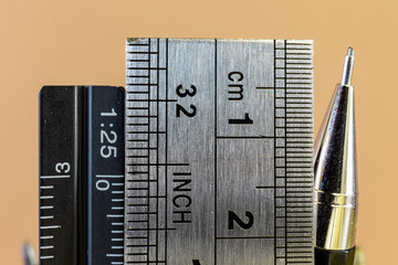 Rulers and mechanical pencil macro image in yellow background. High quality steel technical drawing tools with different measuring scales.