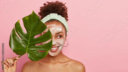 Cuadros en Lienzo Pleased dark skinned woman stands naked alone, looks aside with cheerful express