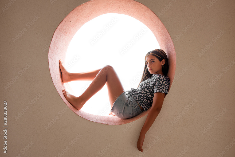 Young barefoot girl resting in a circular opening - obrazy, fototapety, plakaty 