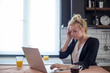 © MexChriss - Young woman having headache while working on laptop.