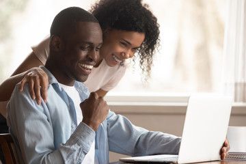 Wall Mural - Excited biracial couple triumph win lottery on laptop online