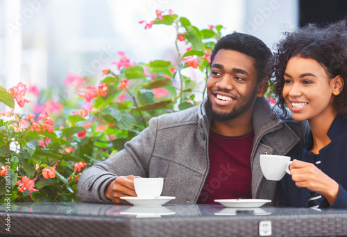 Fotografía Beautiful couple sitting on terrace, watching people on the street