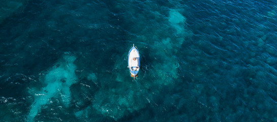 View from above, stunning aerial view of a beautiful fishing boat with a fisherman on board sailing on a blue sea. Amalfi coast, Italy