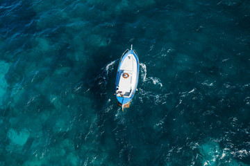 View from above, stunning aerial view of a beautiful fishing boat with a fisherman on board sailing on a blue sea. Amalfi coast, Italy