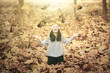 © Creativa Images - Woman playing at park with autumn leaves